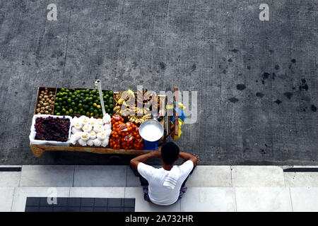 ANTIPOLO CITY, PHILIPPINES - 25 octobre 2019 : vendeur vend Fruits Fruits frais assortis dans son panier alimentaire et attend les clients à un trottoir. Banque D'Images