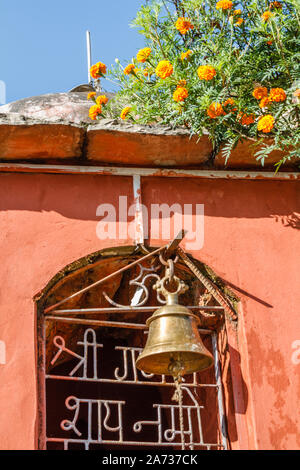 Peu de culte hindou avec une grosse cloche de bronze dans la région de l'Himalaya de montagne. En fleurs fleurs de plus en plus. Le Népal. Vertical image. Banque D'Images