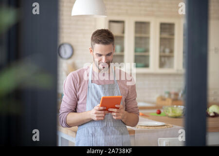 Mari portant un tablier de cuisine recette lecture avant le dîner Banque D'Images