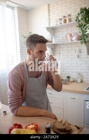 Homme debout dans la cuisine et l'eau potable Banque D'Images