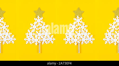 Bannière avec les arbres de Noël créative faite de flocons blancs et décoration de Noël sur fond jaune vif. Mise à plat. Copier l'espace. Banque D'Images