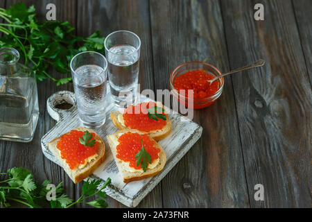 La vodka avec caviar de saumon et de pain grillé sur fond de bois. Boire de l'alcool artisanal pur et des collations traditionnelles. L'espace négatif. La célébration de la nourriture et délicieux. Vue d'en haut. Banque D'Images