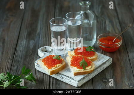 La vodka avec caviar de saumon et de pain grillé sur fond de bois. Boire de l'alcool artisanal pur et des collations traditionnelles. L'espace négatif. La célébration de la nourriture et délicieux. Vue d'en haut. Banque D'Images