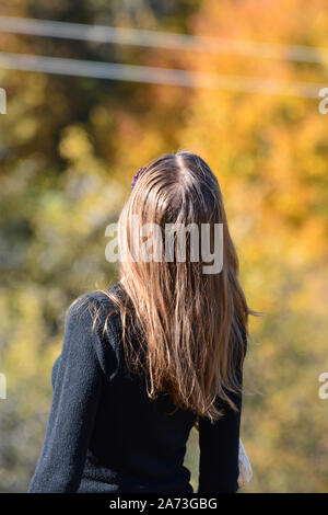 Fille brune aux cheveux longs dans les environs de l'automne, vue de derrière Banque D'Images