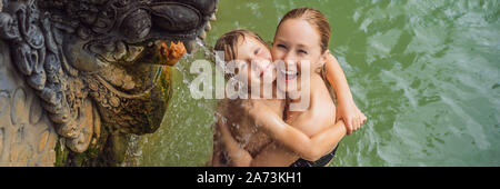 Mère et fils les voyageurs à hot springs banjar. L'eau thermale est sorti de la bouche de statues dans un hot springs de Banjar, Bali, Indonésie Banque D'Images