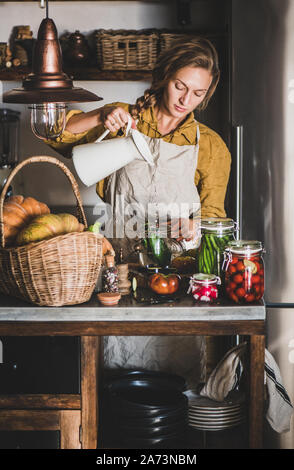 Jeune femme blonde en faisant tablier conserve légumes maison Banque D'Images