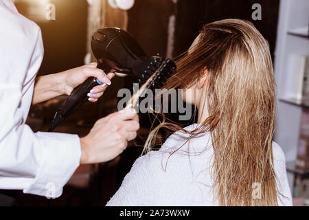 Coiffure cheveux homme blond de séchage avec un sèche-cheveux professionnel dans un salon de beauté. Libre de coiffeur à l'aide de brosse et d'un sèche-cheveux. Banque D'Images