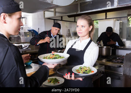 Young waitress préparé des plats du chef en cuisine de restaurant moderne Banque D'Images