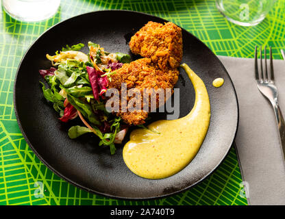 Du poulet tandoori en chapelure panko servis avec mélange de salades et sauce moutarde Banque D'Images