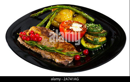 Longe de veau grillé appétissant avec légumes cuits servis avec groseille sur plaque en céramique. Plus isolé sur fond blanc Banque D'Images