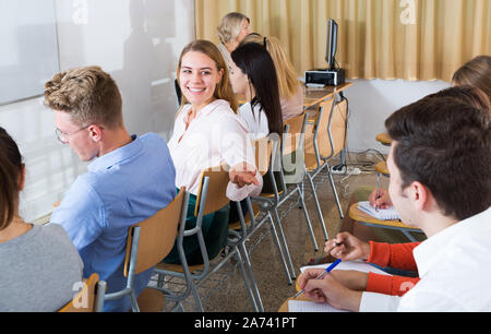 Jeune étudiante Parle avec elle groupmates animée pendant les cours in lecture hall Banque D'Images