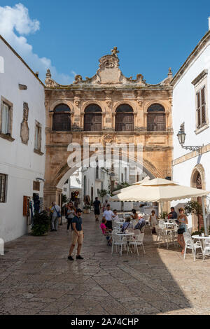 Café en plein air sur Largo Arcid Teodoro Trinchera avec Arco Scoppa (17e siècle arch) en arrière-plan - Ostuni Pouilles (Puglia), dans le sud de l'Italie Banque D'Images