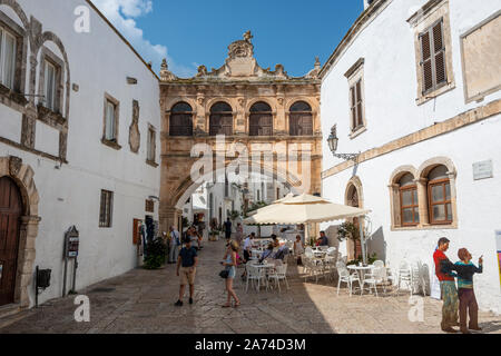 Café en plein air sur Largo Arcid Teodoro Trinchera avec Arco Scoppa (17e siècle arch) en arrière-plan - Ostuni Pouilles (Puglia), dans le sud de l'Italie Banque D'Images