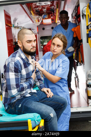 L'équipe d'ambulance soins médicaux aux patients de sexe masculin dans une voiture d'ambulance Banque D'Images