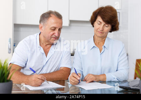 Portrait of mature couple positif au remplissage des documents table de cuisine Banque D'Images