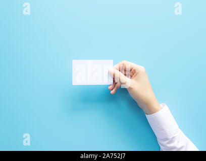 Woman hand holding blank business name card paper isolé sur fond bleu avec copie espace. Banque D'Images