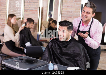 Portrait de main-d'hairstylist et satisfait la clientèle masculine après coupe de cheveux moderne en studio Banque D'Images