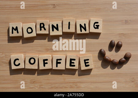 Le café du matin. Mots en lettres de l'alphabet en bois 3d avec les grains de café sur fond de bois de bambou. Banque D'Images