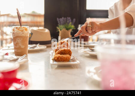 Woman hand holding prise de fourche avec verre sur table. Banque D'Images