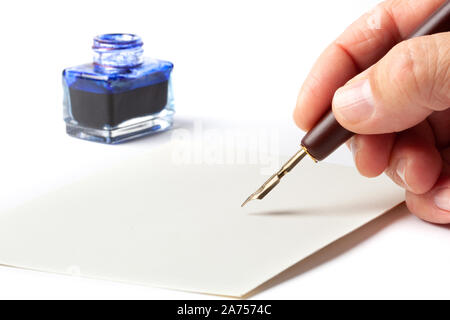 La main avec une vieille fontaine calligraphie stylo à encre sur une enveloppe vide mail isolé sur fond blanc. Banque D'Images