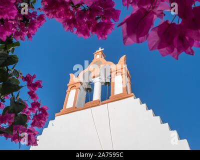 Vue à la recherche jusqu'en haut du clocher de l'église chapelle ciel bleu clair violet rose encadrement par bougainvilliea Santorin branche en fleurs Banque D'Images