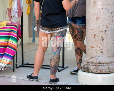 De deux jambes tatouées lourdement de filles de race blanche en short. Festival Arts Alive 2019 Corpus Christi, Texas USA. Banque D'Images