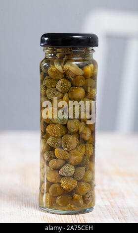 Câpres au vinaigre dans un bocal en verre sur la table en bois Banque D'Images