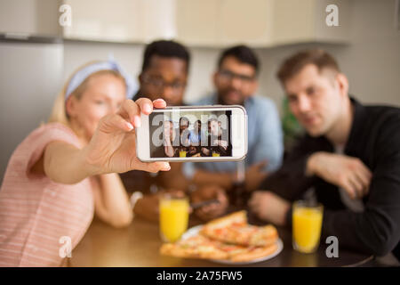 Groupe multiracial d'amis prenant tout en selfies assis à table et en train de déjeuner. Amitié, loisirs et technologie concept. Les étudiants gais havi Banque D'Images