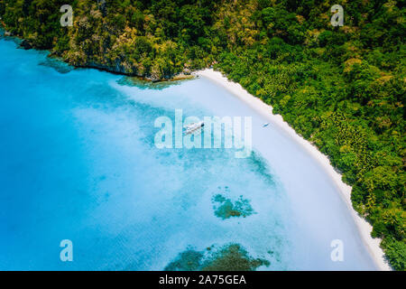 Vue d'en haut de l'antenne de bateau amarré à la plage de sable blanc isolée avec des cocotiers et lagon peu profond bleu turquoise surréaliste autour. Billet d