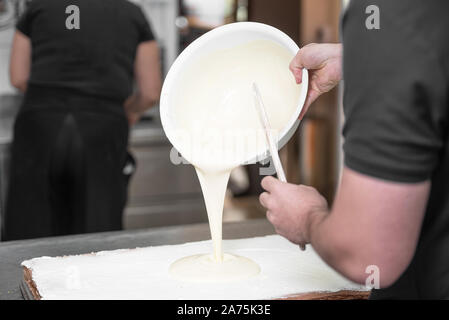 Verser la crème pâtissière chaude. Close up Portrait d'un pâtissier professionnel pour la préparation de desserts au remplissage cuisine étape par étape . Banque D'Images