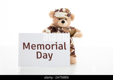 Memorial Day concept. Mignon ours en uniforme de soldat tenant une carte avec texte Memorial Day isolés contre fond blanc, copy space Banque D'Images