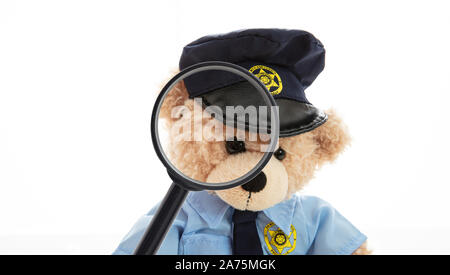 Agent de police ours en uniforme et d'une loupe isolés contre fond blanc Banque D'Images