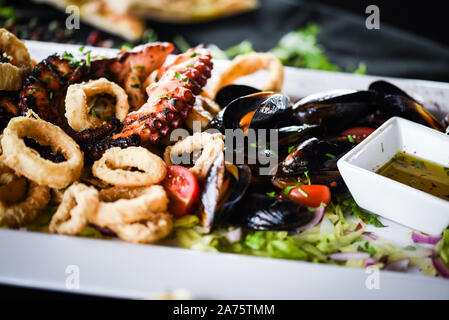 délicieux plat de fruits de mer frits avec poulpe, crevettes, crevettes, coquillages, calmars et poisson frais - avec vinaigrette au citron et aux herbes Banque D'Images