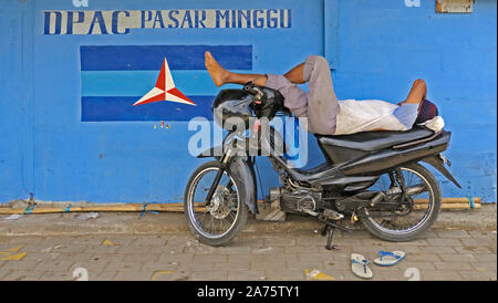 Jakarta, Indonésie - Positions 2009.11.08 : un homme dormant sur sa moto à la gare pasar la semaine ! en face de parti démocratique publicité Banque D'Images