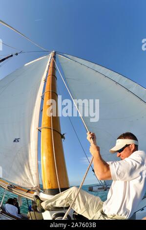 Levage de l'équipage et de voiles avec des cordes sur schooner America 2.0 qui sillonnent les eaux turquoise au coucher de naviguer au large de Key West, Florida Keys, Floride, USA Banque D'Images