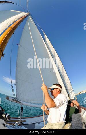 Levage de l'équipage et de voiles avec des cordes sur schooner America 2.0 qui sillonnent les eaux turquoise au coucher de naviguer au large de Key West, Florida Keys, Floride, USA Banque D'Images