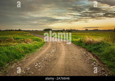 Chemin de terre avec des pierres, d'horizon et les nuages sur le ciel du soir Banque D'Images