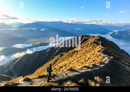 L'homme de la randonnée le long de la crête de la montagne en direction de pic dans la lumière au coucher du soleil. Banque D'Images