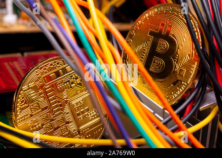 Cryptocurrency virtuelle Bitcoin argent pièces d'or sur un ordinateur de circuits imprimés PCB entouré par différents câbles colorés. L'avenir de l'argent Banque D'Images