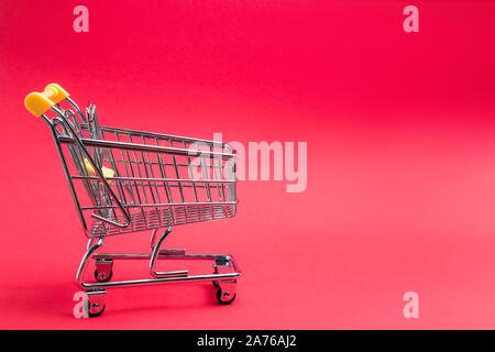 Mini chariot de supermarché isolé sur fond rouge. Concept d'achat en ligne, copier du texte pour l'espace Banque D'Images