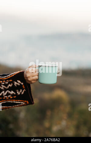 Maquette de femme main tenant une tasse de café vert pastel en céramique dans la nature. Télévision la lumière Banque D'Images