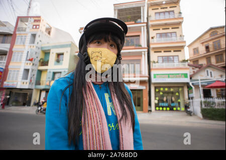 Da Lat, Lam Dong, Vietnam - 20 Février 2011 : fille vietnamienne portant des vêtements d'hiver occasionnels colorés, casque et masque anti pollution jaune Banque D'Images