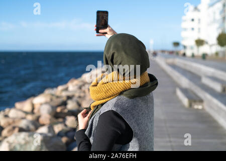 Femme avec foulard en tenant par ocean selfies Banque D'Images