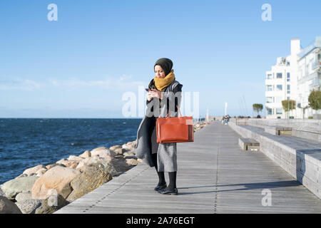 Femme avec foulard en tenant par ocean selfies Banque D'Images