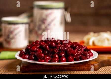 Les cerises pleine plaque sur une planche,container pots, des tranches de banane et un pinceau Banque D'Images