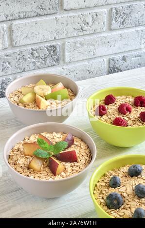 Délicieux doux petit déjeuner sain. Porridge avec différents fruits sur une table de cuisine en bois. Banque D'Images