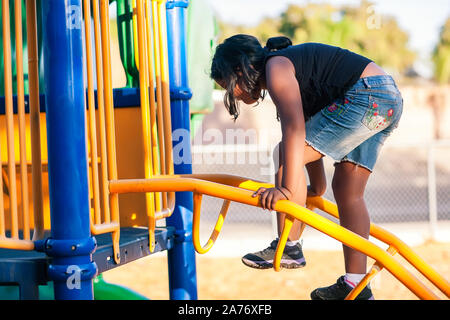 Une jeune fille d'une échelle d'escalade sur une jungle gym et développer son sens de l'équilibre. Banque D'Images