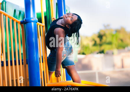 Une mignonne petite fille de s'amuser pendant qu'elle se bloque à partir d'une mini Jungle gym. Banque D'Images