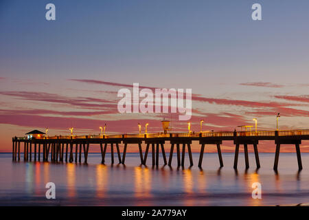 La jetée de pêche au coucher du soleil sur l'Île Okaloosa, Florida, USA, avec boardwalk phares sur montrant les réflexions dans la Floride Golfe du Mexique. Banque D'Images