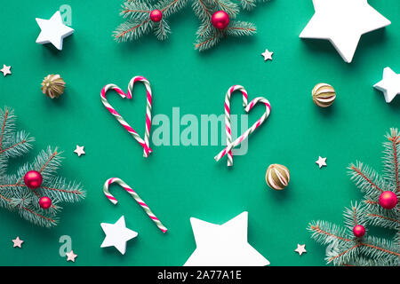 Noël créatif mise à plat avec des brindilles de sapin, des cannes de bonbon organisé que des coeurs, des babioles en verre rouge et de chaux de fruits. Cadeaux de papier en forme d'étoiles. Z Banque D'Images